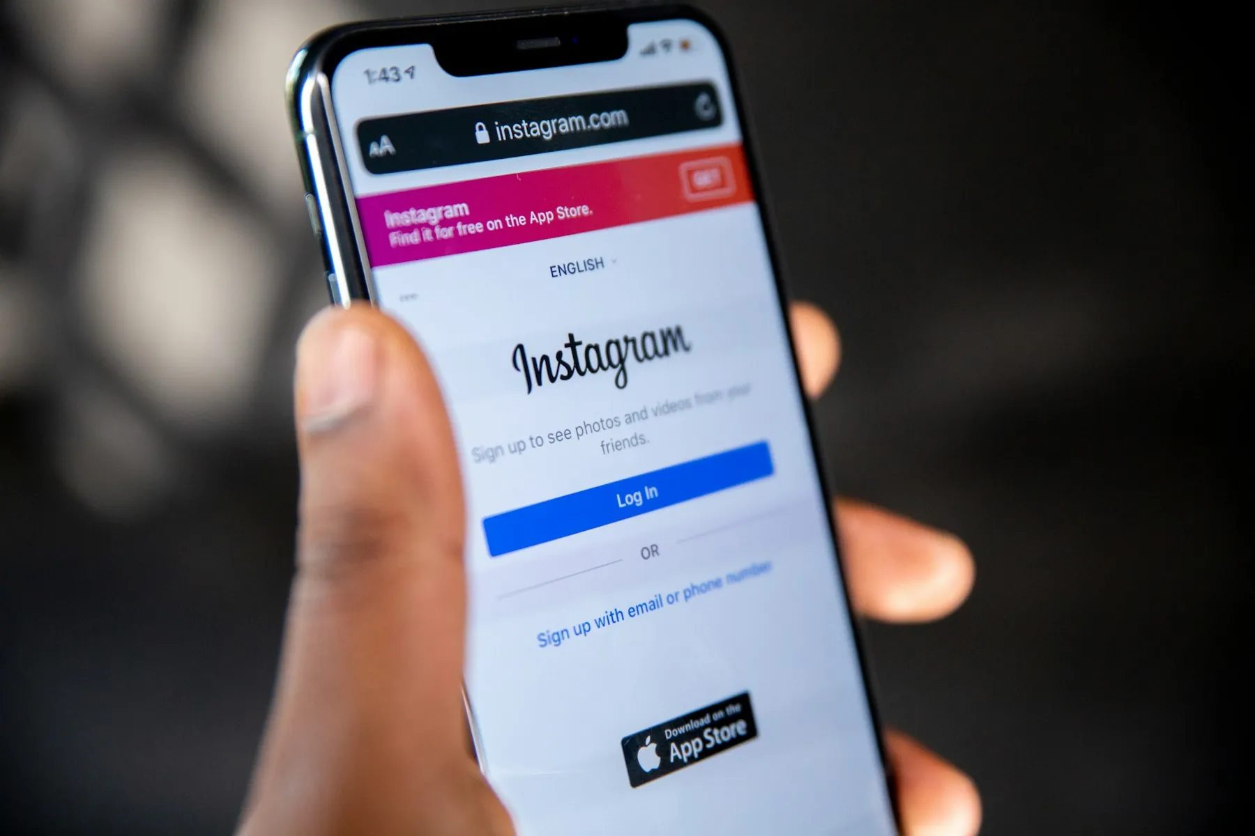 A hand holding a phone showing the Instagram login screen, where social search often starts